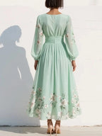 Woman wearing a light green floral v-neck chiffon midi dress - studio photo