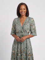 Woman wearing a green floral v-neck elbow-sleeve maxi dress - studio photo