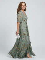 Woman wearing a sage green floral wrap flutter sleeve maxi dress - studio photo
