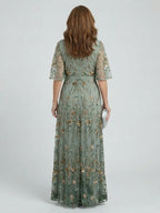 Woman wearing a sage green floral wrap flutter sleeve maxi dress - studio photo