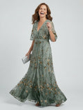 Woman wearing a sage green floral wrap flutter sleeve maxi dress - studio photo