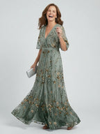 Woman wearing a sage green floral wrap flutter sleeve maxi dress - studio photo