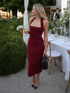 Woman wearing a burgundy halter neck fitted midi dress - editorial style photo