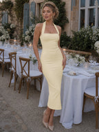 Woman wearing a burgundy halter neck fitted midi dress - editorial style photo
