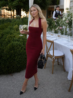 Woman wearing a burgundy halter neck fitted midi dress - editorial style photo