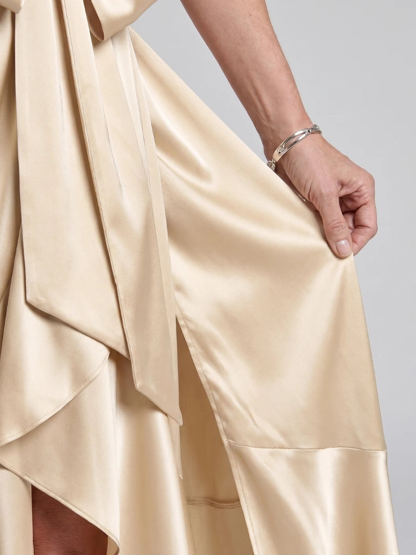 Woman wearing a beige halter wrap asymmetric midi dress - studio photo