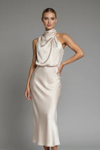Woman wearing a champagne high neck draped front dress - studio photo