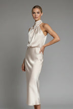 Woman wearing a champagne high neck draped front dress - studio photo