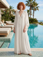 Woman wearing a white lace v-neck batwing sleeve chiffon maxi dress poolside at a resort