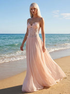 Woman wearing a blush pink lace bustier maxi dress on a beach