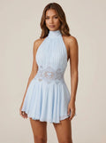 Woman wearing a blue lace-waist halter mini dress in a studio setting