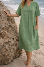 Woman wearing a dark green linen v-neck relaxed midi dress - lifestyle photo