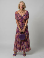 Woman wearing a brown off-shoulder draped midi dress - studio photo