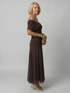 Woman wearing a dark green off-shoulder draped midi dress - editorial style photo