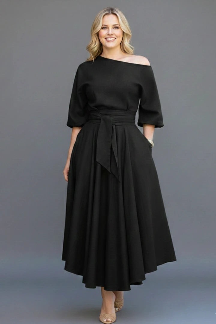 Woman wearing a black off-shoulder lantern sleeve midi dress - studio photo