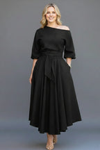 Woman wearing a black off-shoulder lantern sleeve midi dress - studio photo