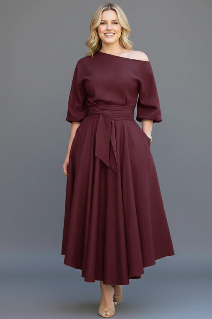 Woman wearing a burgundy off-shoulder lantern sleeve midi dress - studio photo