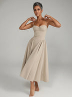 Woman wearing a beige sleeveless corset style midi dress, studio photo, hands on straps pose