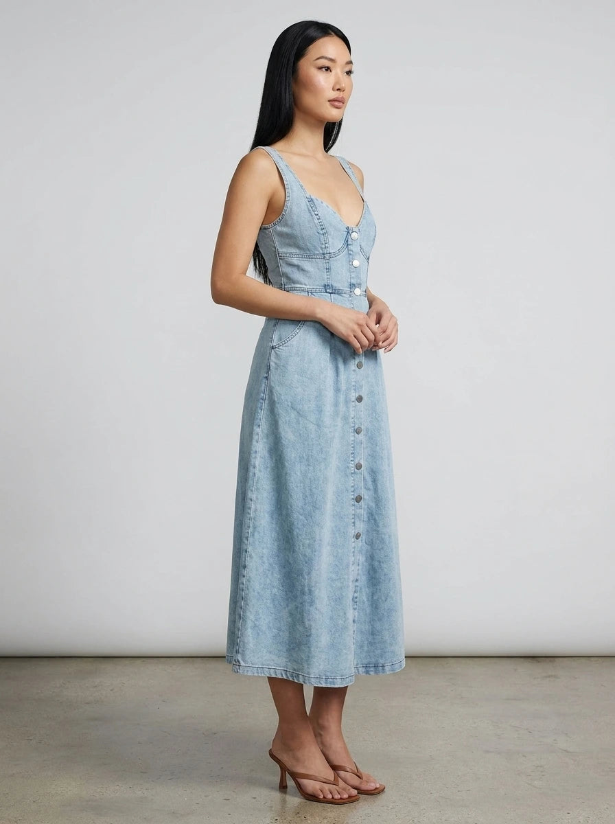 Woman wearing a light blue sleeveless denim midi dress in a studio setting
