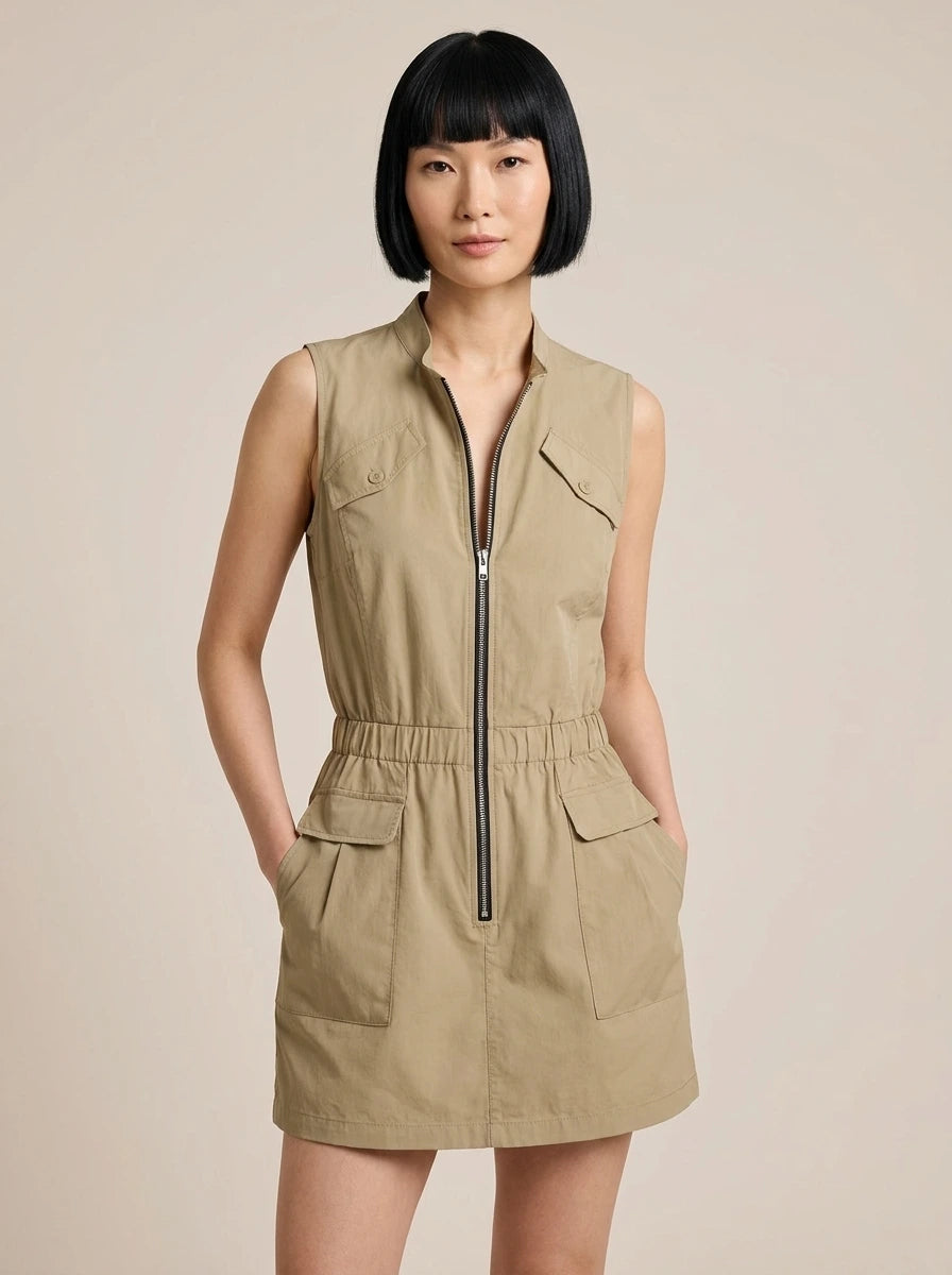 Woman wearing a khaki sleeveless zip-front cargo dress in a studio setting