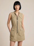 Woman wearing a khaki sleeveless zip-front cargo dress in a studio setting