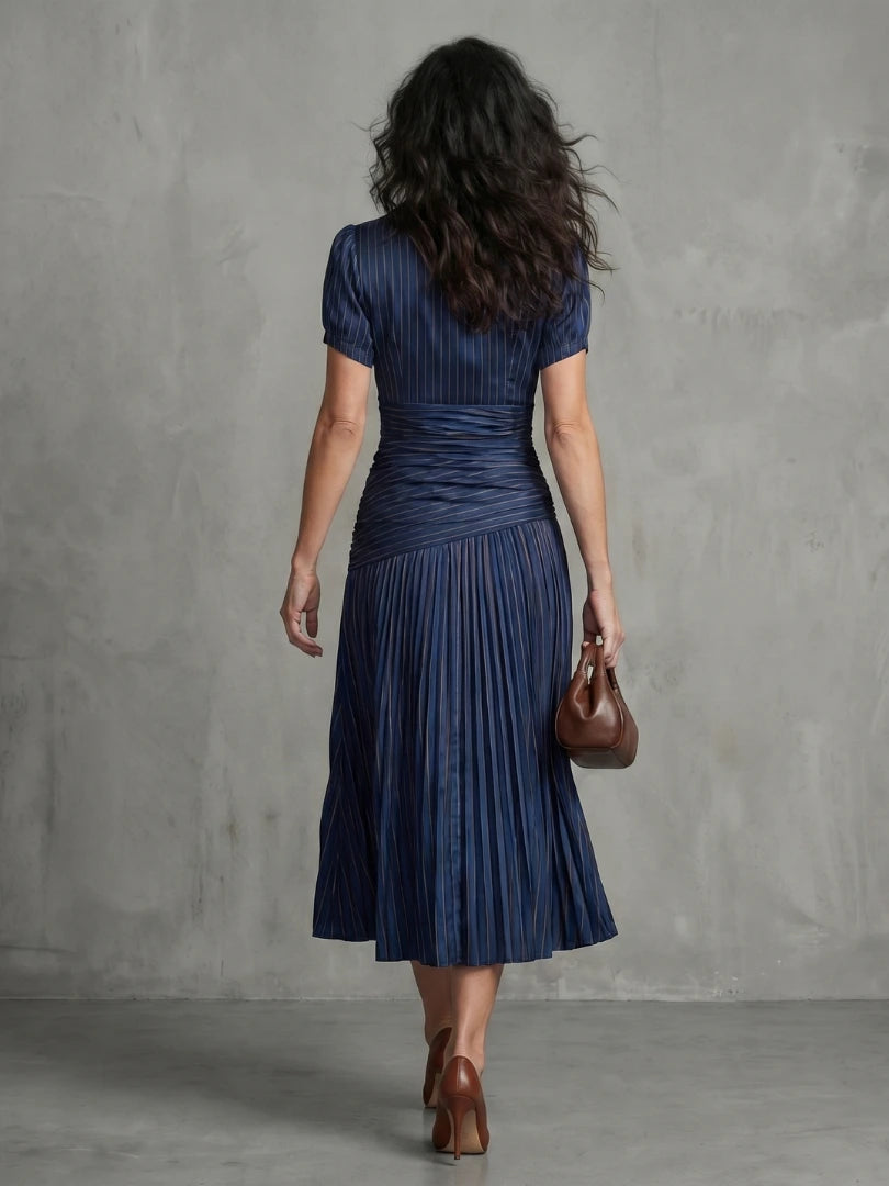 Woman wearing a blue stripe pleated midi dress - studio photo