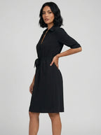 Woman wearing a black v-neck midi dress, studio photo, side pose