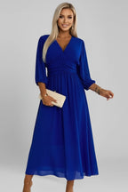 Woman wearing a blue v-neck wrap waist dress - studio photo