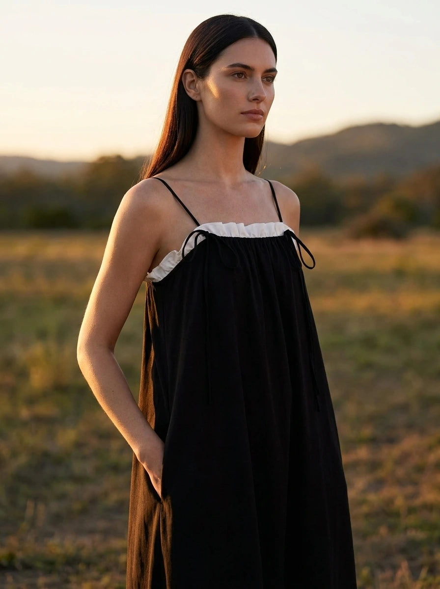 Woman wearing a black color block spaghetti strap maxi dress, outdoor sunset field setting