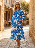 Driftly blue floral button-down midi dress with lapel collar, long sleeves, and adjustable waist tie, on a European street at golden hour.