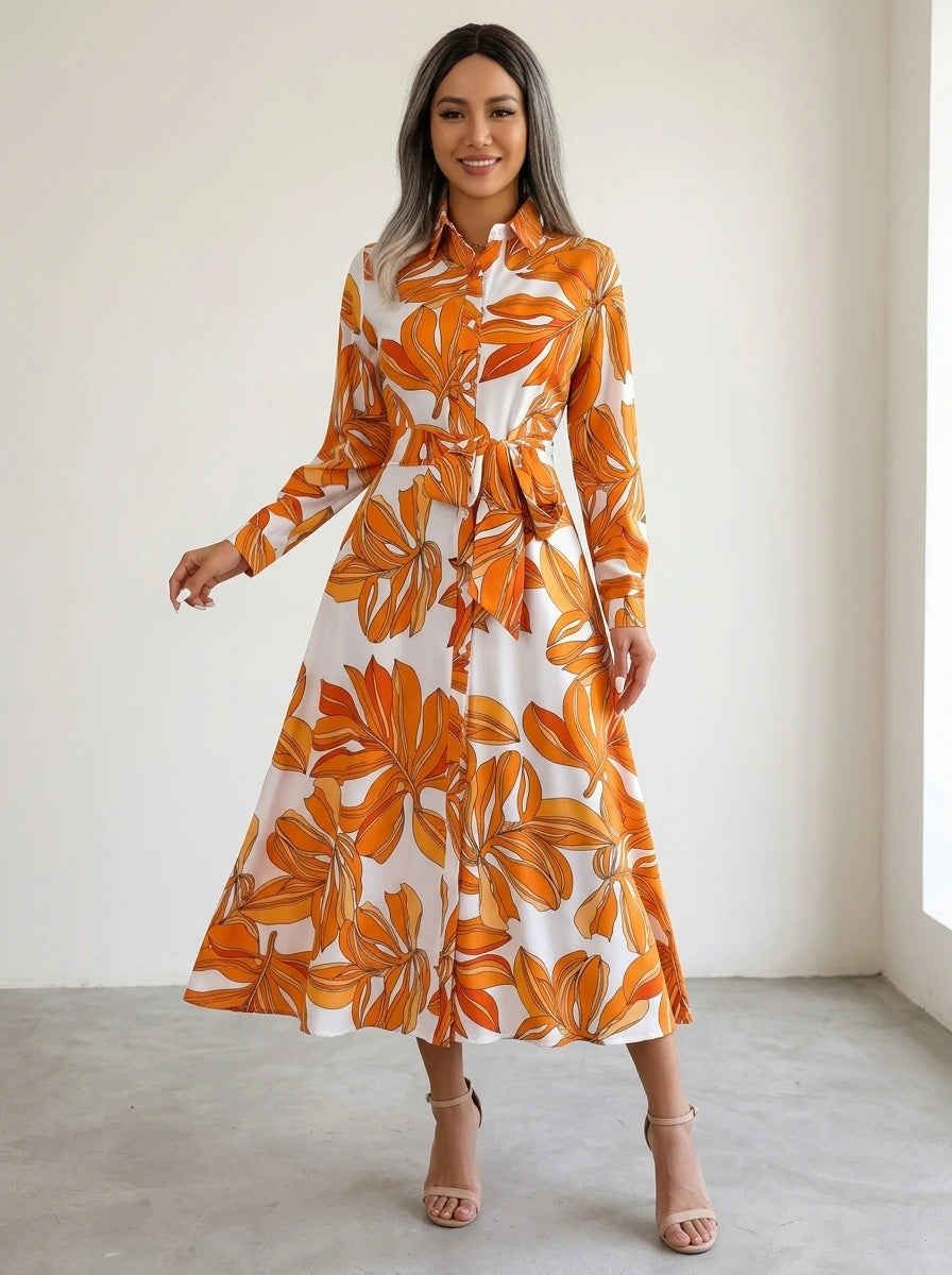 Driftly orange floral button-down midi dress with lapel collar, long sleeves, and adjustable waist tie, in a minimalist studio setting with soft window light.