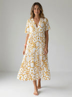 Driftly yellow floral V-neck midi dress, bohemian style, soft-blend fabric, in a minimalist studio setting with soft window light.