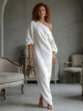 Woman wearing a white one-shoulder maxi dress, indoor setting