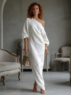Woman wearing a white one-shoulder maxi dress, indoor setting