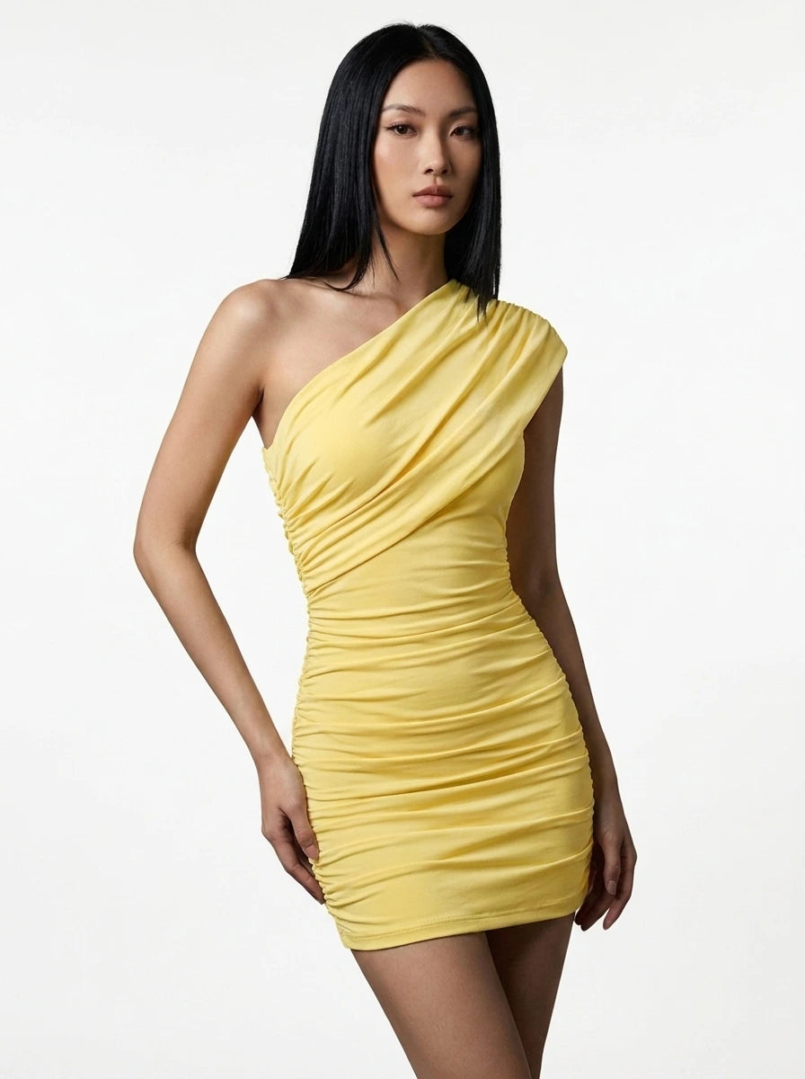 Woman wearing a yellow one-shoulder ruched mini dress with asymmetric neckline in a studio setting