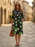 Driftly black polka dot collared midi dress with partial button front, three-quarter rolled sleeves, and side pockets, on a European street at golden hour.