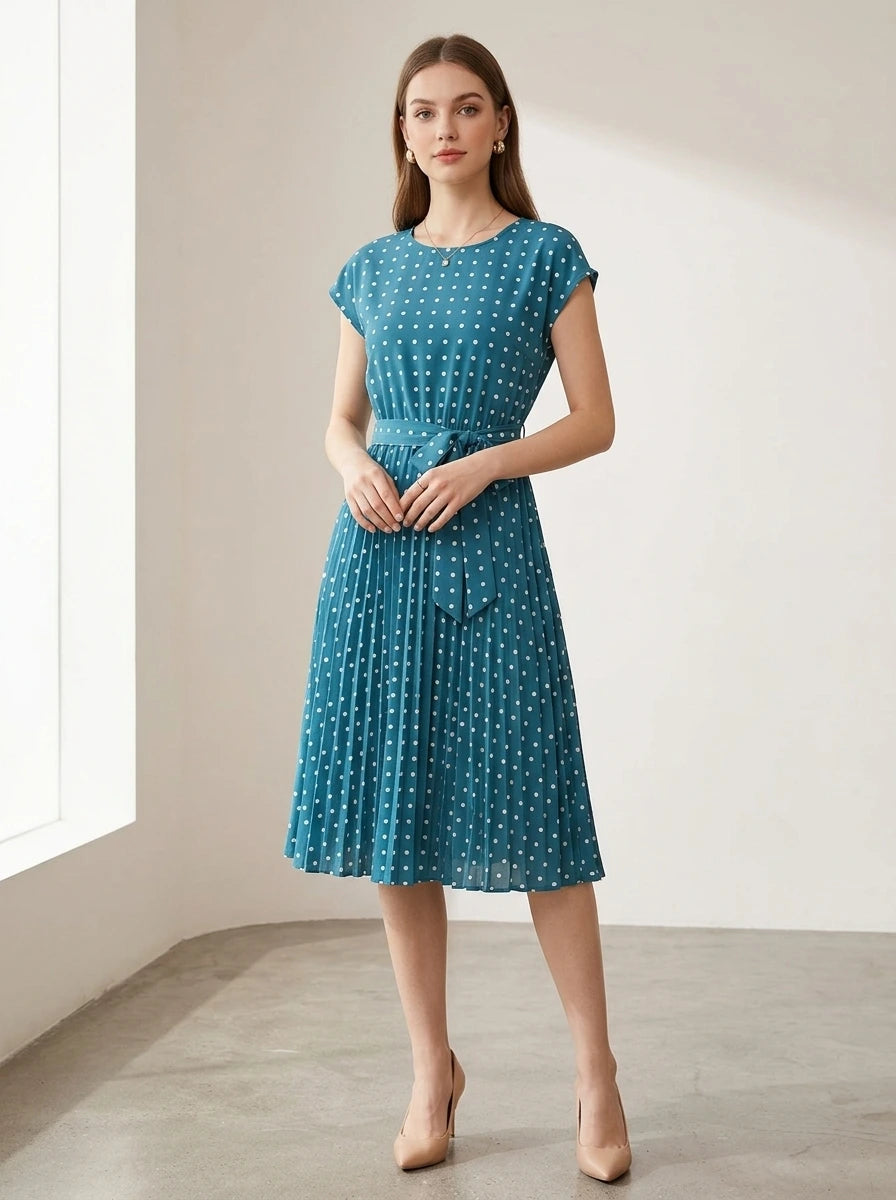 Driftly fancy blue polka dot pleated midi dress with cap sleeves and a self-tie waist belt, in a minimalist studio setting with soft window light.