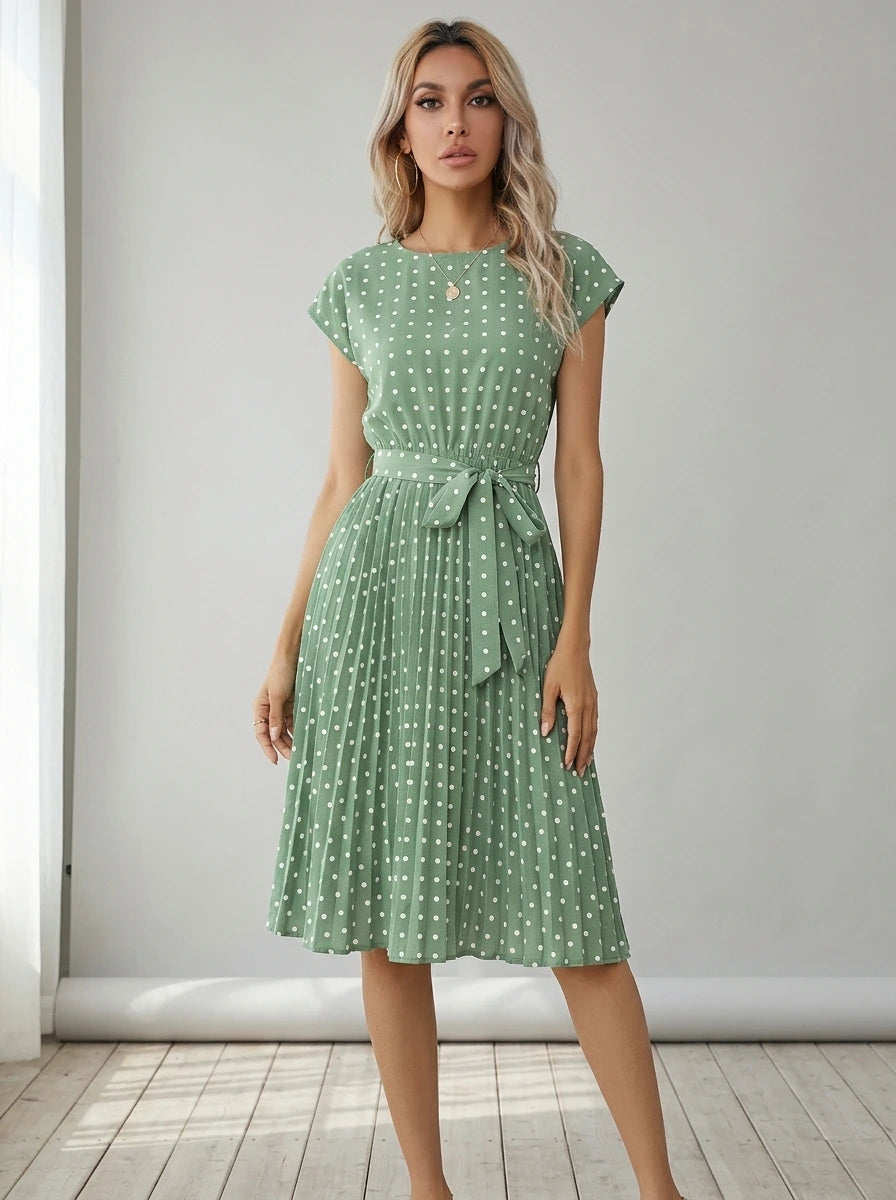 Driftly mint green polka dot pleated midi dress with cap sleeves and a self-tie waist belt, in a minimalist studio setting with soft window light.