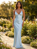 Woman wearing a light blue satin maxi dress with thin straps in a sunlit garden