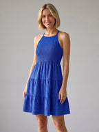 Woman wearing a blue smocked tiered mini dress in a studio setting