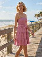 Woman wearing a pink smocked tiered mini dress at the beach