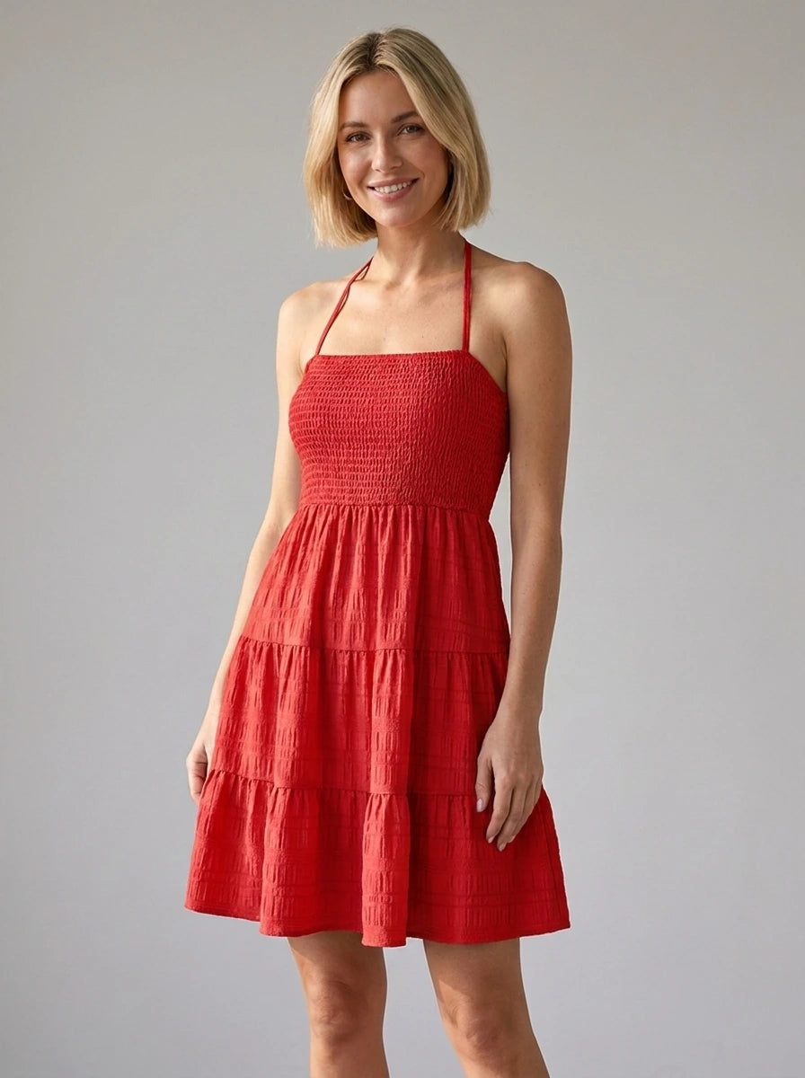 Woman wearing a red smocked tiered mini dress in a studio setting
