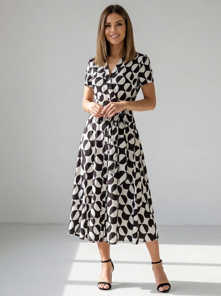 Driftly women's black and white geometric print V-neck A-line maxi dress with button-up front and tie waist, in a minimalist studio setting.