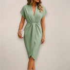 Woman wearing a sage green wrap midi dress - studio photo