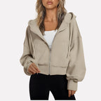 Woman wearing a beige cropped zip hoodie in a studio setting