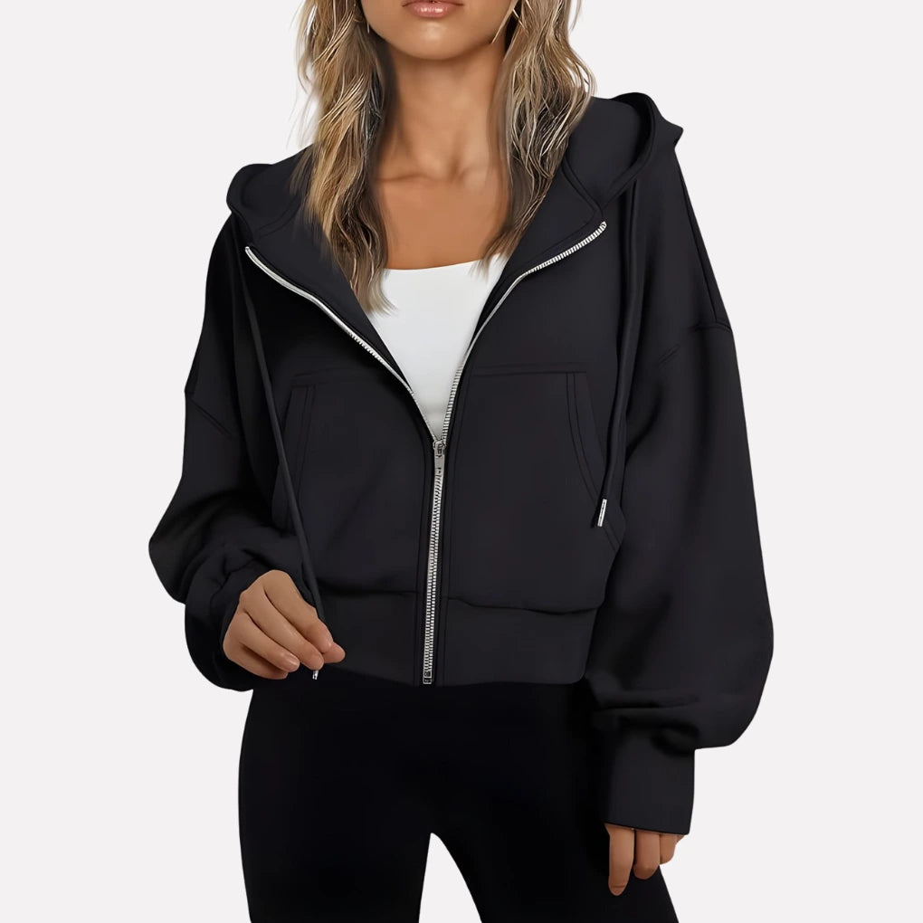 Woman wearing a black cropped zip hoodie in a studio setting