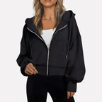 Woman wearing a black cropped zip hoodie in a studio setting