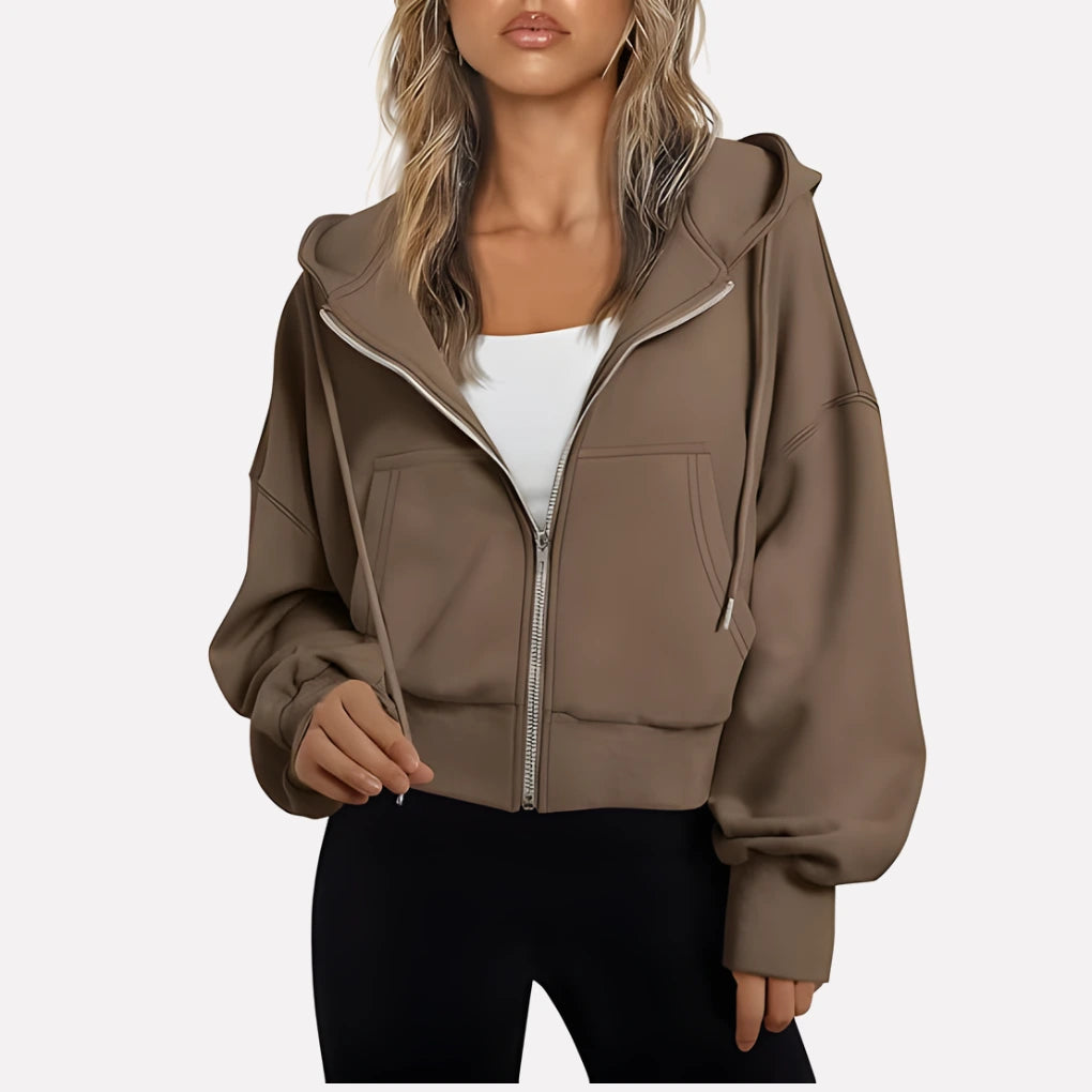 Woman wearing a brown cropped zip hoodie in a studio setting
