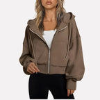 Woman wearing a brown cropped zip hoodie in a studio setting