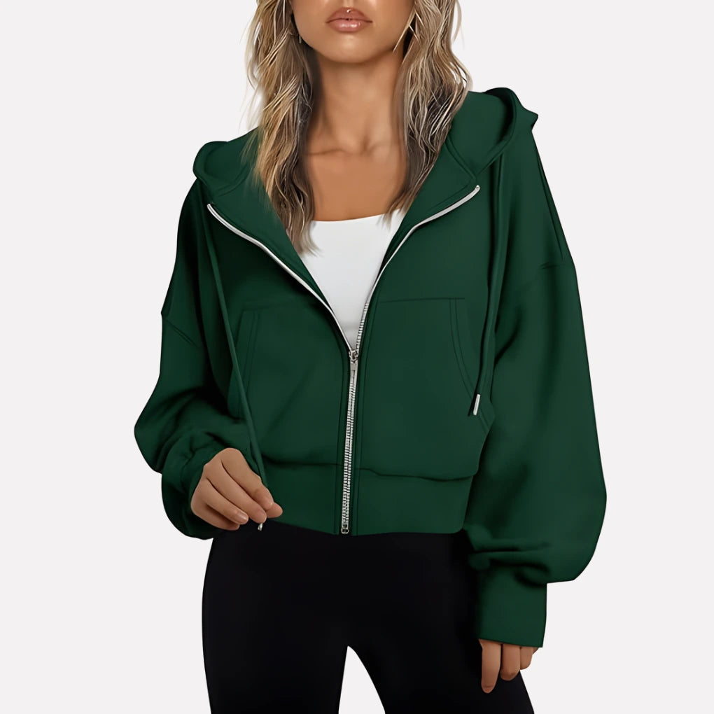 Woman wearing a dark green cropped zip hoodie in a studio setting